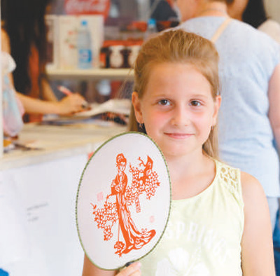 在“北京日”老字号展卖活动中，一位俄罗斯小朋友购买了一把工艺品扇子。 　　本报记者 王斯雨摄