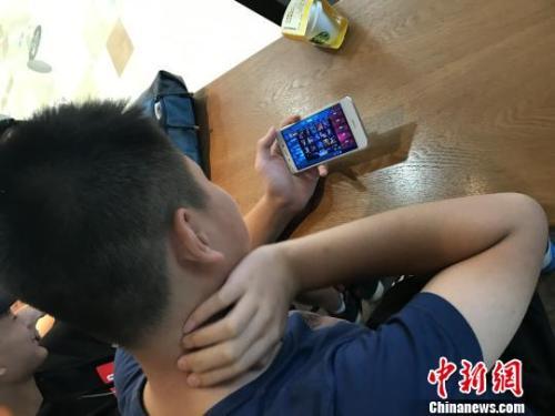 资料图：学生在玩热门手机游戏?！∷辗捎?摄