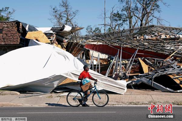 图为当地时间10月14日，男子骑车经过一片废墟。