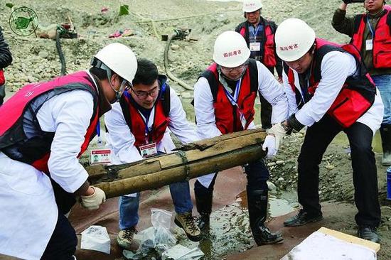 图说：考古人员将木鞘搬离发现地点。