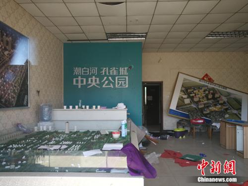 从一家已经关门的售楼处门外望进去，地上散落着废纸、条幅，沙盘上放着落灰的杀虫剂。<a target='_blank' href='http://www.chinanews.com/' >中新网</a>记者 邱宇 摄