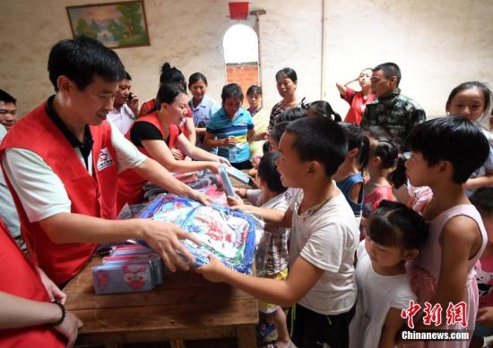志愿者向留守儿童赠送书包、文具盒。 周亮 摄