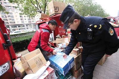 11月8日，城管执法人员协助快递人员将包裹搬离人行道。