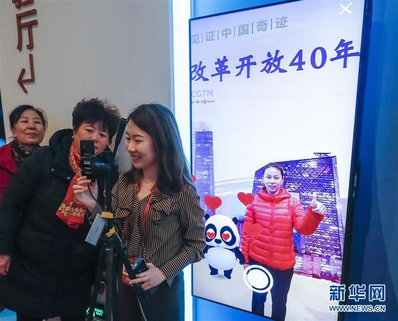 11月20日，在 “伟大的变革——庆祝改革开放40周年大型展览”的壮美篇章展区，观众在体验中央广播电视总台的AR体验项目，与一只“CGTN熊猫”互动，并拍摄照片。