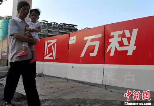 资料图：福州民众从万科楼盘工地旁经过。<a target='_blank' href='http://www.chinanews.com/'>中新社</a>记者 张斌 摄