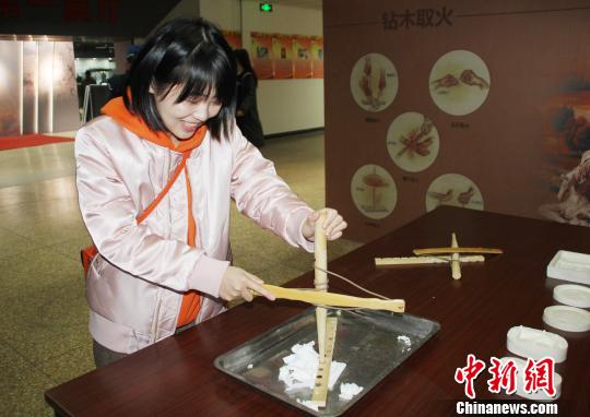 参观者现场体验“钻木取火”。　徐巧明 摄