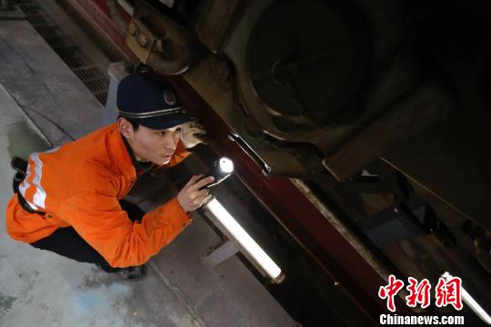 动车机械师正在检修动车车底部件。　丁波 摄