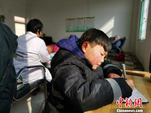 在社区服务中心，刘奉智母亲为村里人按摩，刘奉智在一旁写作业。　郝学娟 摄