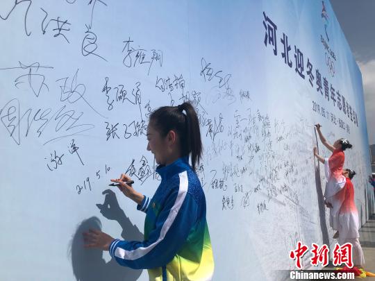 图为河北迎冬奥青年志愿者、张家口机械工业学校教师游洋在启动仪式现场主题背景墙上签名?！∷蚊籼?摄