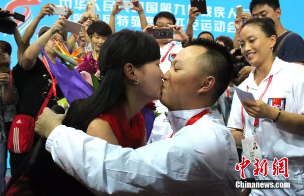 2015年9月18日，在地震中失去双腿的四川游泳队运动员“无腿蛙王”代国宏，在残运会赛场向女友苏思妙求婚成功。中新社发 钟欣 摄