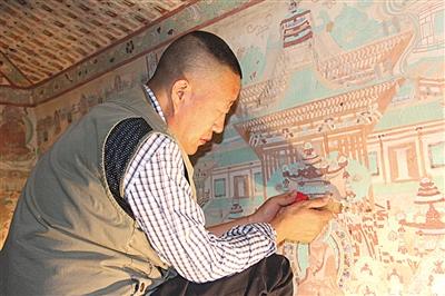 李波在修复壁画。图片来源:新京报 点击进入下一页
