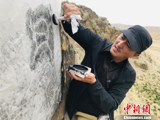 图为杜成峰按照岩画线条走向用拓包开始描边?！《涞?摄
