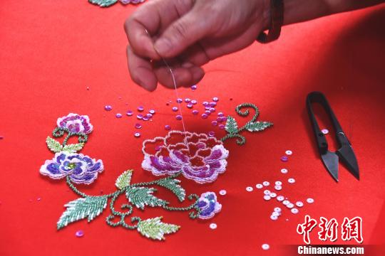 在绣工的穿针引线下，花朵逐渐“绽放”在罗缎上?！〕铝?摄