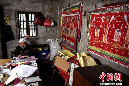 盘良安的“工作室”内堆满了祭祀用的道具、典籍，墙上张贴着盘王图。　李凌 摄