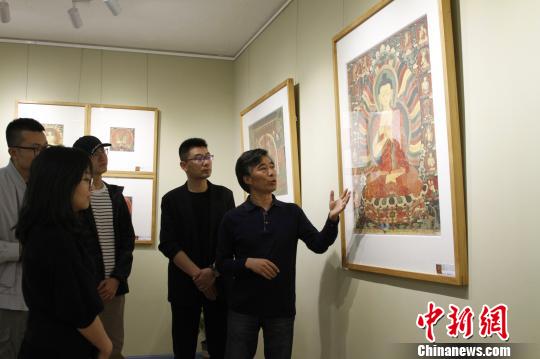 图为主创者高志勇向参观嘉宾介绍拍摄作品。　赵朗 摄