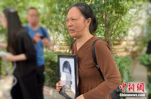 谢雕母亲带着谢雕的遗照走出法院 <a target='_blank' href='http://www.chinanews.com/' >中新网</a> 杨雨奇 摄 点击进入下一页