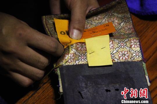 图为罗布林卡管理处工作人员将编号缝在古籍外侧?！≌岳?摄