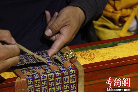 图为罗布林卡管理处工作人员将普查登记完的一函古籍封装?！≌岳?摄