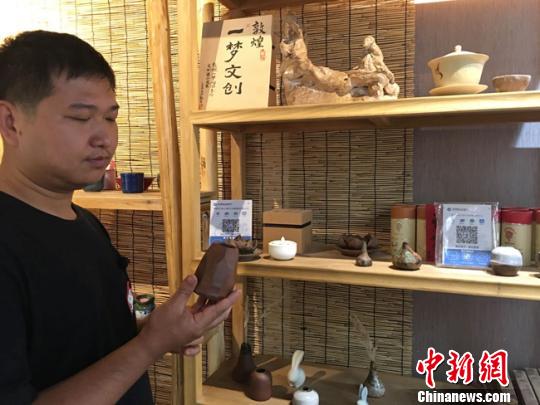 图为月牙泉小镇上的敦煌文化痴迷者叶金盛展示文创产品?！≌沛?摄