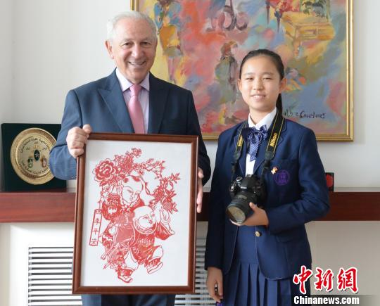 “2019丝路新语？中外文化小使者巡礼”活动在京启动。图为中国文化小使者向摩洛哥王国驻华大使阿齐兹？梅库阿尔赠送中国剪纸。主办方供图