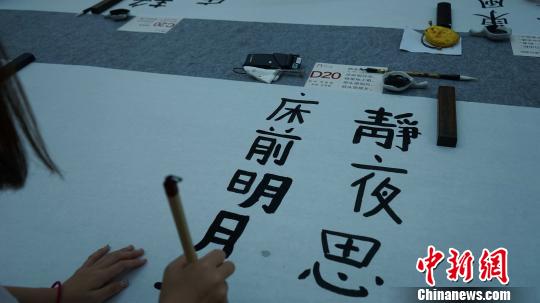 图为中日韩青少年正在用毛笔书写唐诗?！〉程镆?摄
