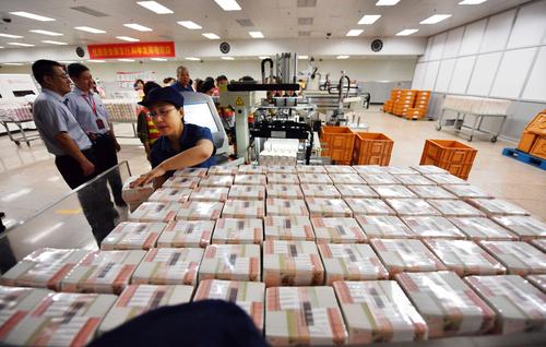 工作人员对塑封好的20元钞票进行封装操作。