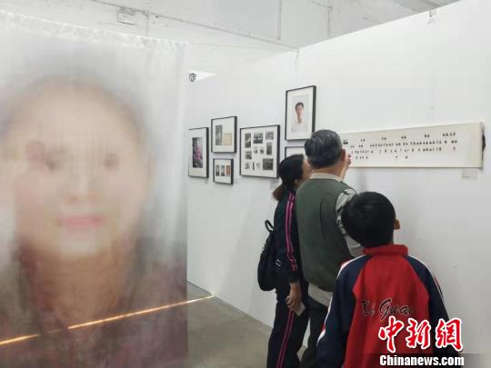 在第19届中国平遥国际摄影大展柴油机展区的一角，一张大幅的人像彩画吸引来往游客驻足拍照。　杨佩佩 摄