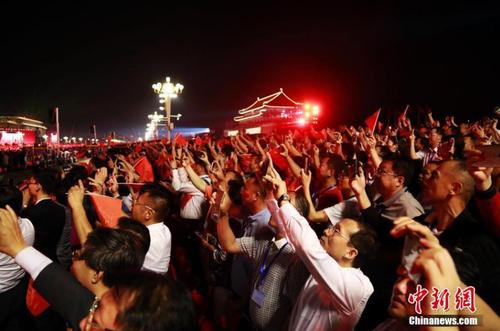 国庆70周年联欢活动于10月1日晚8时在天安门广场举行，整个联欢活动由主题表演、中心联欢表演、群众联欢、烟花表演四个功能表演区组成。图为民众观看璀璨烟花。中新社记者 汤彦俊 摄