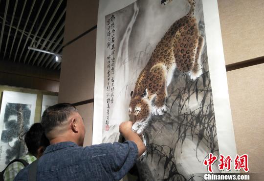 观众欣赏六尺国画挂轴《豹子觅泉图》。主办方供图
