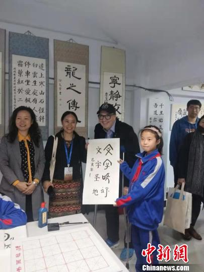 图为外国汉学家与孩子交流书法?！⊙畲笥?摄