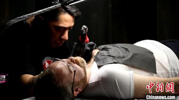 “TukuIho生生不息”毛利文化展上，毛利手工匠帮观众纹纹身。　金杨 摄