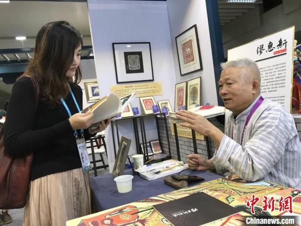 秀洲农民画画家缪惠新和参观者交流。供图