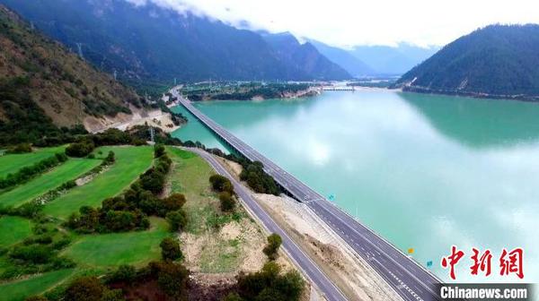 涉藏纪录片《极地通途》于12月9日在《西藏卫视》首播，讲述人与公路的故事。图为横跨在碧湖上高等级公路(12月9日 纪录片截屏图) 纪录片制作方供图 摄