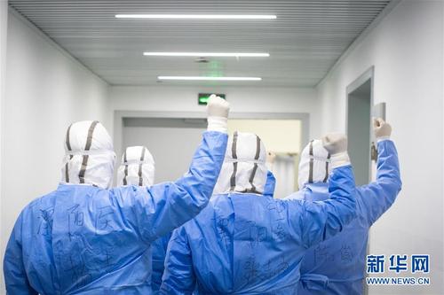 2月17日，来自江苏医疗队的杨洁、张志俊、李飞、汤建伟、陈俊在进舱前加油打气。 武汉体育中心方舱医院从2月12日收治首批患者以来，运行平稳有序，患者在医护人员的精心照顾下调养身体，等待痊愈。记者夜晚来到武汉体育中心方舱医院，用镜头记录舱内瞬间。 新华社记者肖艺九摄