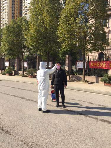 图为杨伟伟的弟弟在下沉社区帮助进入人员测体温。