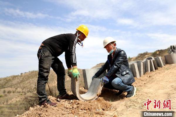 专业工人将水泥排水管手工搬运到排水道内。　于晶 摄
