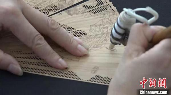 邢伟中的徒弟向观众展示檀香扇制作过程中的“烫花”过程。　徐明睿 摄