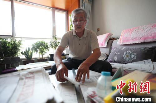 李竹庭正在用尺子撕扯报纸?！∮诰?摄