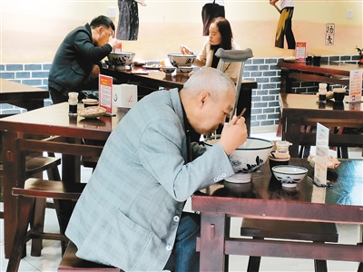 一位残疾老人正在店里吃面