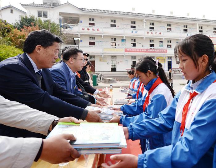 北京公益服务发展促进会常务副会长兼秘书长、北京市昌平区政协委员孙鹏飞（左二）及出席捐赠仪式的嘉宾向小学生捐赠图书