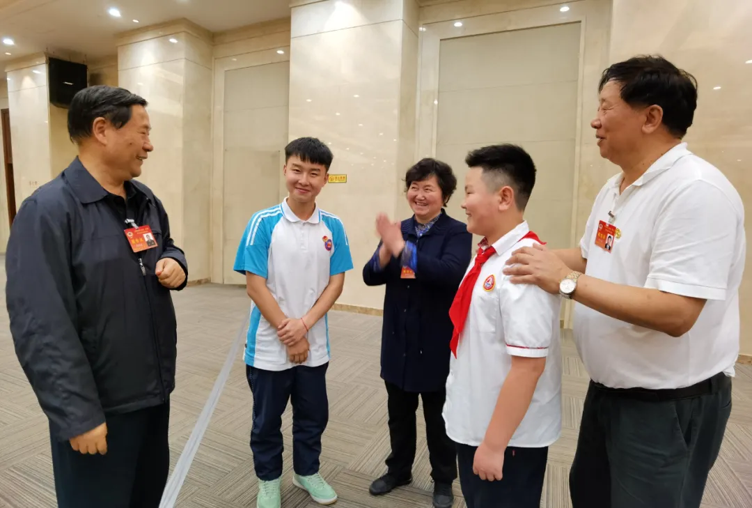 全国政协常委戚建国（左一）、全国政协文化文史和学习委员会副主任叶小文（右一）与学生亲切交谈