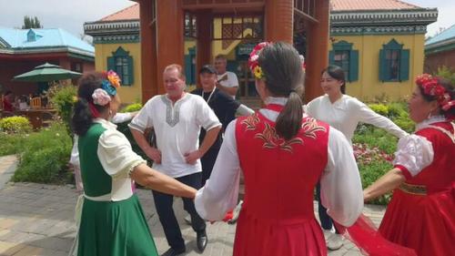 △在六星街俄罗斯风情园，皮特罗·克拉斯娜乌索夫（中间舞者）与记者欢快地跳起了舞蹈。