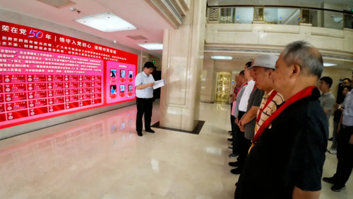 老党员们来到“光荣在党50年”荣誉墙前，庄重地贴上写有自己名字的荣誉牌。