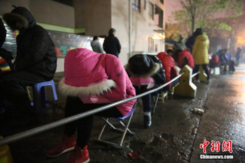 2016年4月6日，在西安市丈八四路缤纷南郡小区内的幼儿园后门附近，家长排队等待报名入园。图片来源：视觉中国