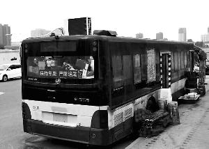 路边停放的公交车顶上的空调十分显眼，旁边码放着座椅、遮阳棚、啤酒等物?？导?摄